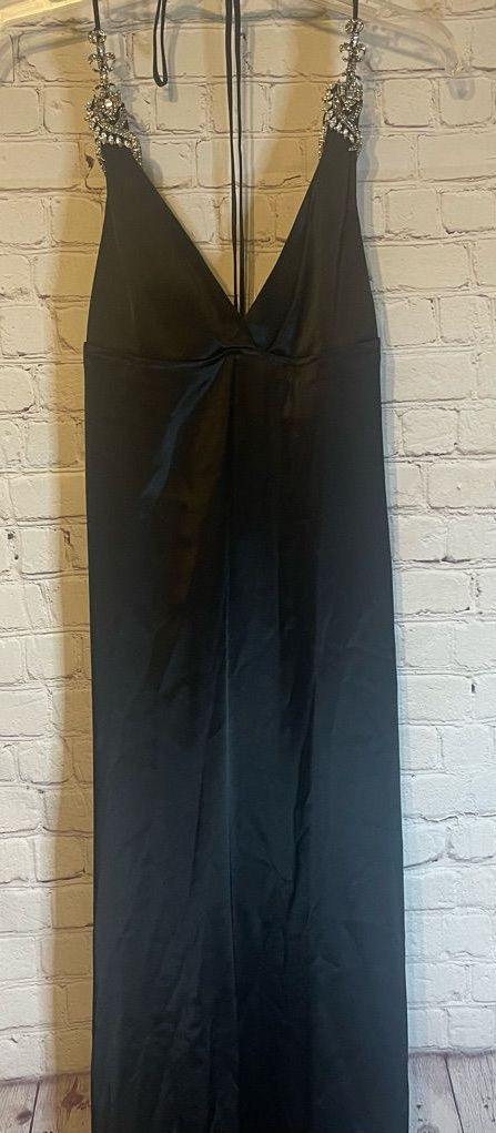 Full-length black satin halter gown hanging, with soft folds down the skirt.