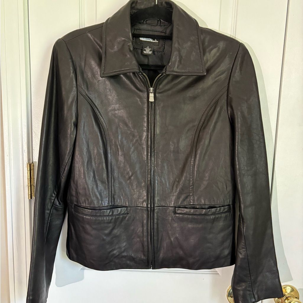 Black cropped leather jacket hanging front-facing, with its collar, sleeves, zipper and hem visible.