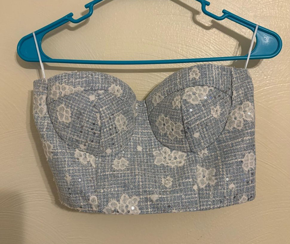Blue floral tweed bustier on a hanger, with structured seams and sequin detailing.