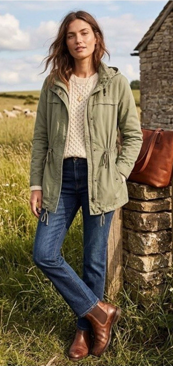 Sage-green hooded anorak with a drawstring waist, styled over a cream sweater and jeans.