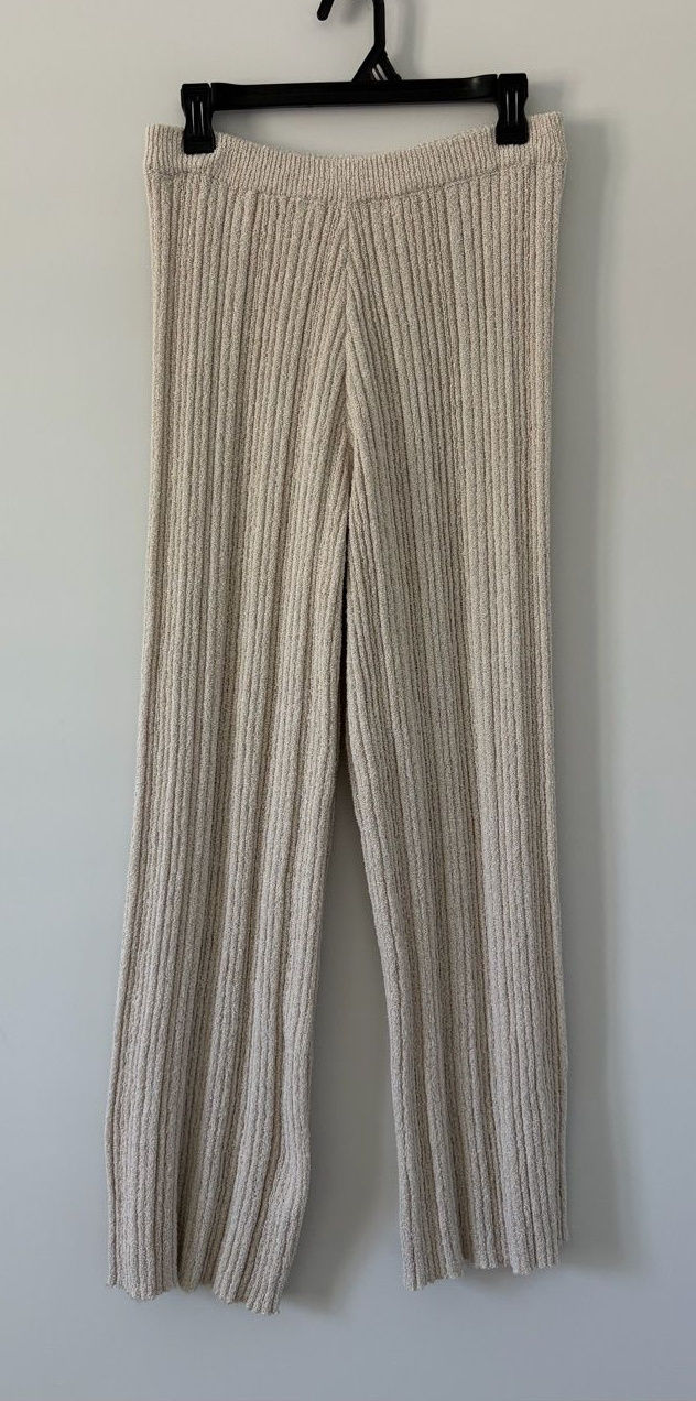 Oatmeal ribbed-knit wide-leg pants hanging against a light wall.