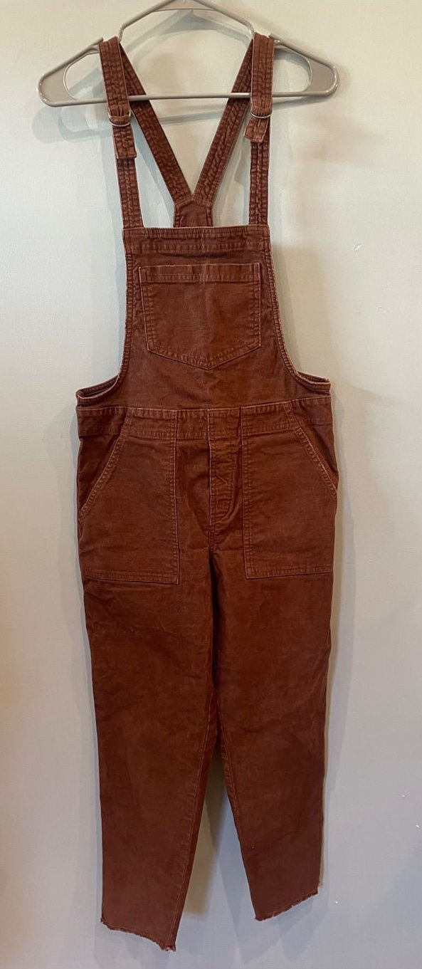 Rust-brown corduroy bib overalls with adjustable straps, pockets, and full-length legs.