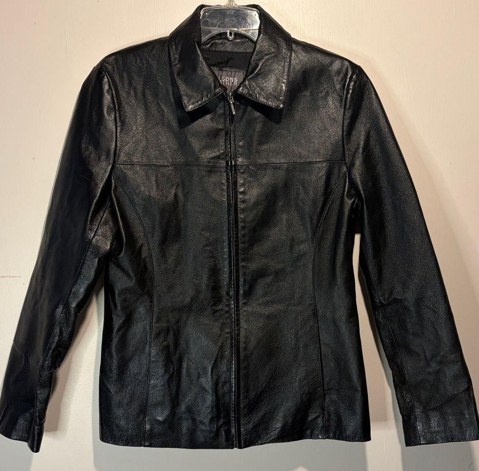 Black leather zip-front jacket laid flat, showing its structured shape and short hem.