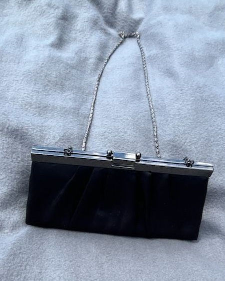 Closed black satin evening clutch with a silver kiss-lock frame and clasp.