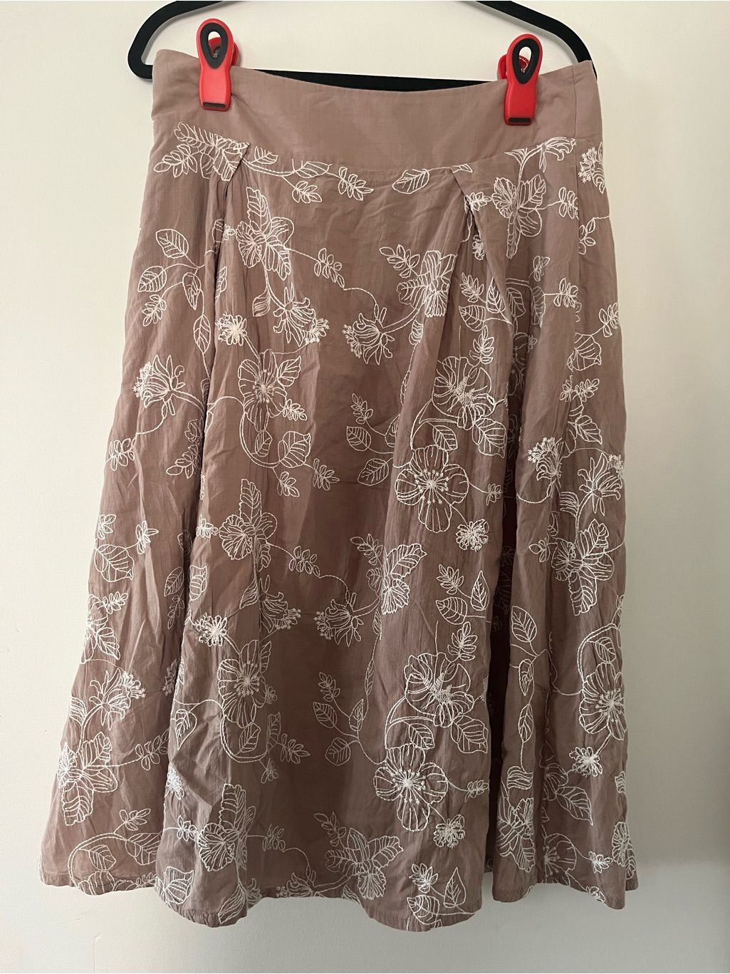 Flowy brown midi skirt with scrolling white floral embroidery.