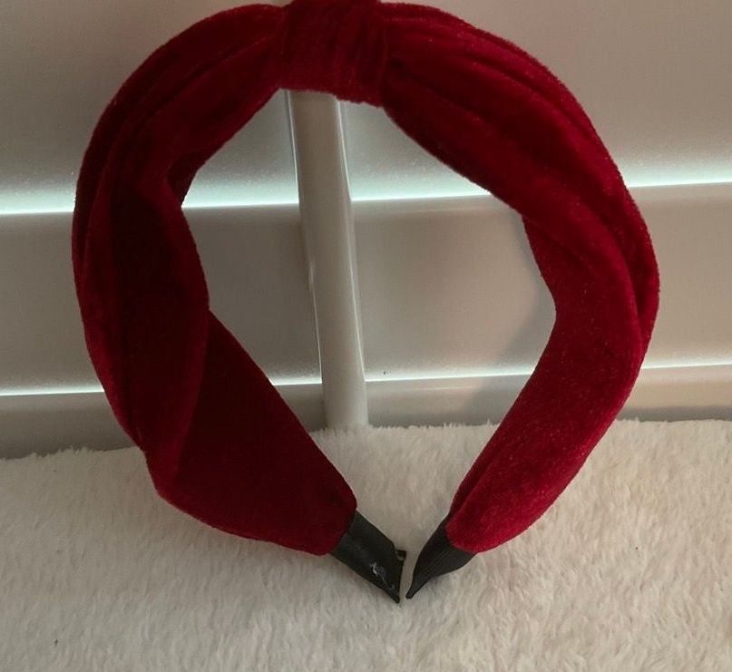 Deep red velvet padded headband shown upright, revealing its curved shape and plush texture.
