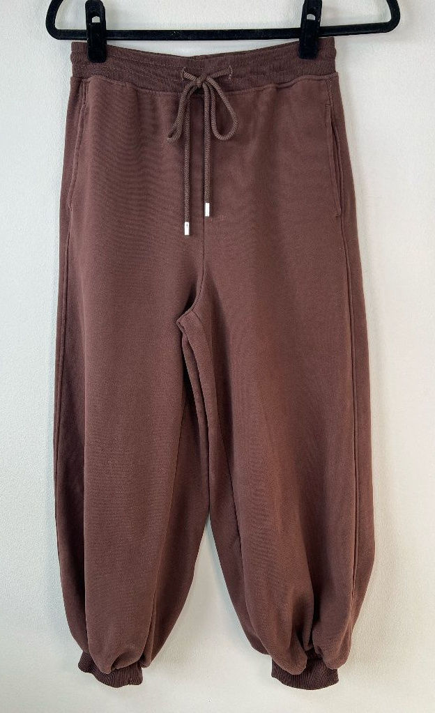 Brown barrel joggers hanging full length, with curved legs narrowing into elastic ankle cuffs.