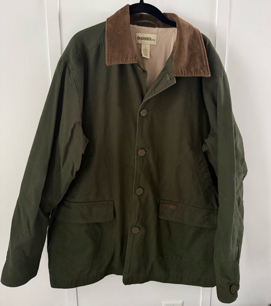 Olive green barn jacket with a contrasting brown corduroy collar and roomy flap pockets, shown on a hanger.