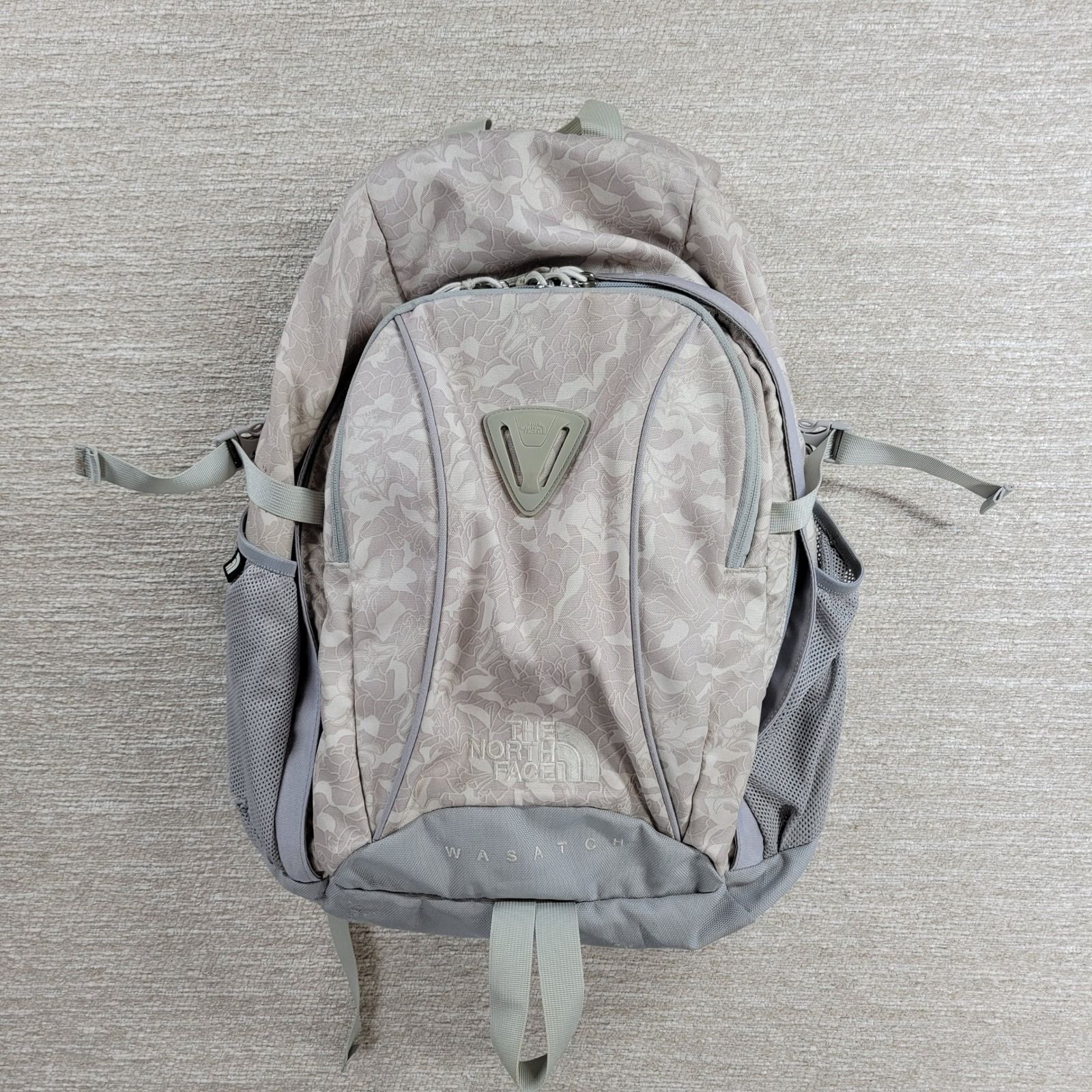 Beige-and-gray daypack with mesh bottle pockets on both sides and adjustable shoulder straps.