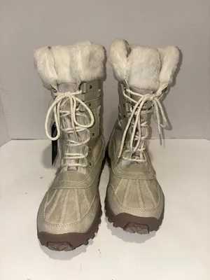 U.S. Polo Assn. Women's Yvonne Snow Boots in an "Oatmeal" or beige colorway. These mid-calf winter boots feature a duck-toe rubber shell base for slush protection, a quilted canvas shaft, traditional lace-up closure, and a plush faux-fur collar trim. A signature metallic logo plaque is attached to the side strap thumbnail 5