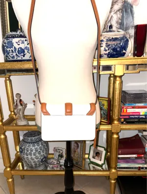 White and brown crossbody bag with adjustable strap. The design features a front flap with a brown leather detail and a clip closure. thumbnail 3