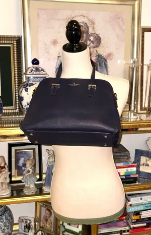 This bag is a Kate Spade Cedar Street Maise satchel in navy blue with gold-tone hardware, made of Saffiano leather, with a top zip closure and top handles. thumbnail 1