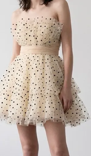 strapless tulle mini dress featuring a cream or light beige mesh fabric adorned with classic black polka dots. It is designed with a heavily ruched, pleated sweetheart bodice, a defined cinched waistband, and a voluminous tiered ruffled skirt. thumbnail 1