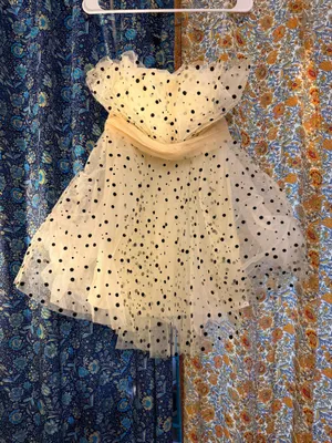 strapless tulle mini dress featuring a cream or light beige mesh fabric adorned with classic black polka dots. It is designed with a heavily ruched, pleated sweetheart bodice, a defined cinched waistband, and a voluminous tiered ruffled skirt. thumbnail 2