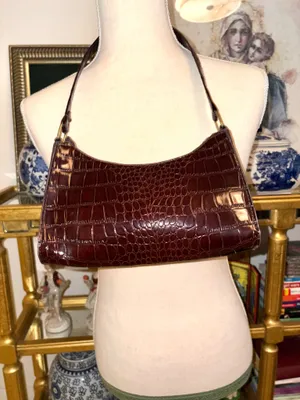 Baguette-style bag with a glossy crocodile-effect finish in a wine-colored tone. It features a minimalist, curved design popular in fashion-inspired thumbnail 2