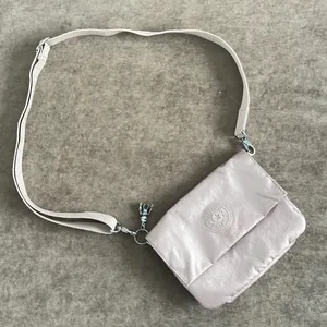 Kipling crossbody purse. Adjustable strap. Flap over closure w/ snap. Light pink thumbnail 1