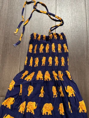 Flowy halter maxi dress with a smocked bodice. Navy base with repeating golden elephant motif. Decorative border print at hem. Lightweight and breezy. Adjustable tie straps. thumbnail 2