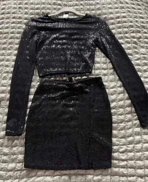 Windsor Black sequin two-piece skirt set with long-sleeve crop top and matching skirt. Sleek, sparkly fabric creates standout evening style. Comfortable fit with a polished, modern silhouette. Perfect for parties and special occasions. thumbnail 1