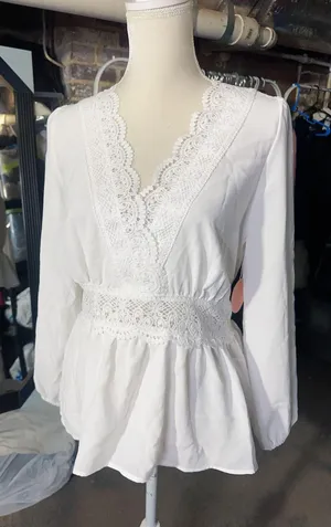 LOS ANGELES white lace V-neck long sleeve shirt top peplum tie cuff New with tag Smoke and pets free Same day shipping Elevate your wardrobe with this stunning white lace blouse from . The V-neckline and long sleeves add a touch of elegance to this top, while the peplum and tie cuff details create a flattering silhouette. The angel character and rose theme make it perfect for any occasion, from casual outings to formal events. Crafted from high-quality lace fabric, this blouse features adjustable features and is available in size S. The solid pattern and delicate lace accents make it a versatile piece that can be paired with any bottom. Whether you're dressing up or down, this Rose & Grey blouse is sure to turn heads. thumbnail 1