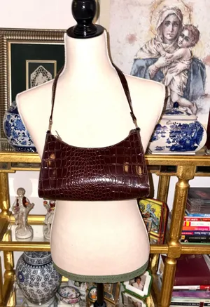 Baguette-style bag with a glossy crocodile-effect finish in a wine-colored tone. It features a minimalist, curved design popular in fashion-inspired thumbnail 1