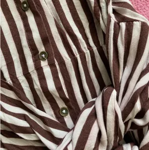 Jen’s Pirate Booty Amaya brown and white striped mini dress in size XS. This has only been worn once and has no rips, tears, or stains. Some color transfer between stripes from washing but it’s not really noticeable as seen in photos. The waist can be tied in front with excess or in back (I like to go around twice and tie in back). Ultra soft and flowy material, love this dress and only selling as it just isn’t quite my style. Measures 30” long, 17” across chest, 14” across at waist, 22” long sleeve (from shoulder seam). thumbnail 3