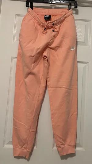 NIKE size small Soft fleece joggers in a warm peach-coral shade. Elastic waistband with adjustable drawstring. Tapered legs with cuffed ankles. Embroidered Nike logo at hip. Cozy everyday women small brand new thumbnail 1