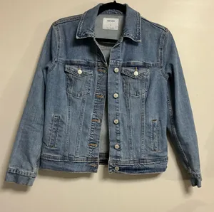 The Old Navy Blue Denim Trucker Jacket is a classic button-up long sleeve jacket in a traditional trucker style. Made from denim, manufactured in Bangladesh.Pit to pit: 18 in. Length: 20 in. Pre-owned with no visible wear. Buttons are all intact and the jacket lays flat with no distortion thumbnail 1