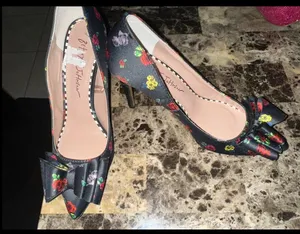 These are Betsey Johnson 'Bret' pumps featuring a black satin upper with a colorful floral print and a prominent bow detail on the pointed toe. thumbnail 2