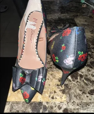 These are Betsey Johnson 'Bret' pumps featuring a black satin upper with a colorful floral print and a prominent bow detail on the pointed toe. thumbnail 3