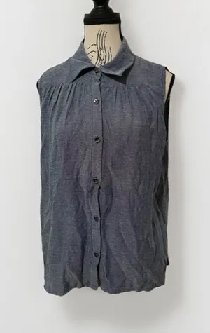 The Cabi Chambray Sleeveless Blouse in blue is a stylish and versatile top perfect for summer, fall, or spring. With a collared neckline, button closure, and ruffle accents, this high-low shirt features a cutout back for added interest. thumbnail 1
