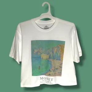 NWOT Monet Art Crop T Shirt White Graphic Tee The Beach Falaise d’Amont This NWOT Monet Art Crop T Shirt in white features a graphic design inspired by The Beach Falaise d’Amont 1889, making it a stylish and artistic addition to any woman's wardrobe. Made from 100% cotton, this regular fit tee has a crew neckline and a cropped style for a modern and trendy look. Perfect for art enthusiasts or those looking to add a unique touch to their outfit, this T-shirt is comfortable and versatile, ideal for everyday wear. thumbnail 2