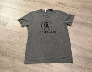 Cooper Alan Graphic Tee Heather Gray Women's Size Large Add this fan-favorite Cooper Alan graphic t-shirt to your collection! This official merchandise features the iconic "CA" logo in a circular crest on the chest, printed on a premium Bella + Canvas heather gray tee. Crafted for comfort, it has a classic crew neck and short sleeves, making it perfect for concerts or everyday wear. • Size: Large • Condition: Excellent pre-owned condition—worn but shows no flaws and is in perfect shape. • Brand: Bella + Canvas (Cooper Alan Merch) • Material: Soft, breathable cotton-poly blend. thumbnail 2