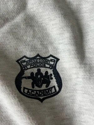 Comfortable light gray crewneck sweatshirt with a small embroidered crest on the chest. Soft, durable fabric for everyday wear. Ribbed cuffs and hem provide a secure fit. Neutral light gray pairs easily with casual outfits. thumbnail 2