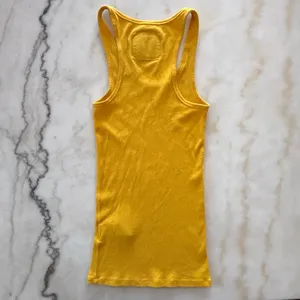 Y2K aesthetic with this classic vintage Abercrombie & Fitch tank top. This piece features a vibrant marigold yellow hue in a flattering, stretchy ribbed knit that's perfect for layering or wearing solo. thumbnail 4