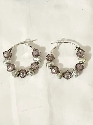 These handmade beaded hoop earrings feature a unique combination of purple, gray, and silver tones. The faceted beads add a touch of bohemian style, making them a perfect gift for someone who loves one-of-a-kind accessories. The handmade quality adds a personal touch to these earrings, making them a standout piece for any jewelry collection. thumbnail 6