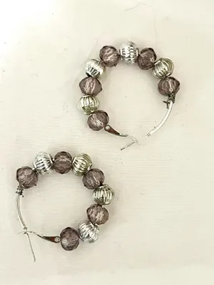 These handmade beaded hoop earrings feature a unique combination of purple, gray, and silver tones. The faceted beads add a touch of bohemian style, making them a perfect gift for someone who loves one-of-a-kind accessories. The handmade quality adds a personal touch to these earrings, making them a standout piece for any jewelry collection. thumbnail 4