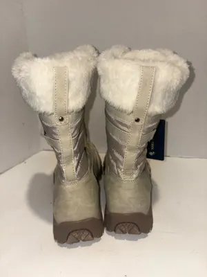 U.S. Polo Assn. Women's Yvonne Snow Boots in an "Oatmeal" or beige colorway. These mid-calf winter boots feature a duck-toe rubber shell base for slush protection, a quilted canvas shaft, traditional lace-up closure, and a plush faux-fur collar trim. A signature metallic logo plaque is attached to the side strap thumbnail 3