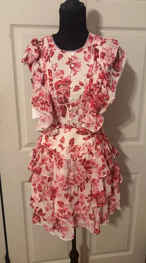 New with tags Ever New Astrid Ruffle Tiered Mini dress in size 4. This garment has a red peony blossom floral print on a light background. It is designed with a button-front bodice, ruffled cap sleeves, and a tiered skirt. The back features a large open cutout with tie closures at the neck and waist. thumbnail 1