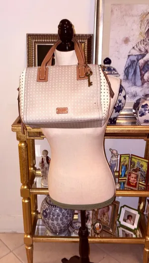 The Fossil Emma Satchel bag in white and gray with a polka dot print and brown leather handles stands out for its classic key charm. thumbnail 1