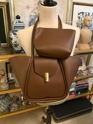 This brown bag features a minimalist design with gold details and a spacious structure. Made from 100% polyurethane, it has a magnetic closure with a gold-tone latch. Designed as a tote or shoulder bag, it's versatile for everyday use or travel. thumbnail 3