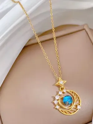 This gold-plated necklace features a celestial-themed pendant with a blue gem representing a planet surrounded by a crescent moon. thumbnail 1