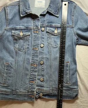 The Old Navy Blue Denim Trucker Jacket is a classic button-up long sleeve jacket in a traditional trucker style. Made from denim, manufactured in Bangladesh.Pit to pit: 18 in. Length: 20 in. Pre-owned with no visible wear. Buttons are all intact and the jacket lays flat with no distortion thumbnail 5