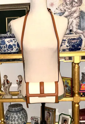 White and brown crossbody bag with adjustable strap. The design features a front flap with a brown leather detail and a clip closure. thumbnail 1