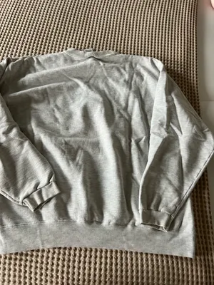 Comfortable light gray crewneck sweatshirt with a small embroidered crest on the chest. Soft, durable fabric for everyday wear. Ribbed cuffs and hem provide a secure fit. Neutral light gray pairs easily with casual outfits. thumbnail 4