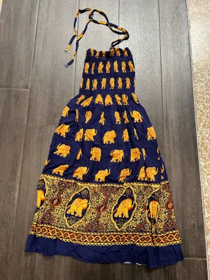 Flowy halter maxi dress with a smocked bodice. Navy base with repeating golden elephant motif. Decorative border print at hem. Lightweight and breezy. Adjustable tie straps. thumbnail 1