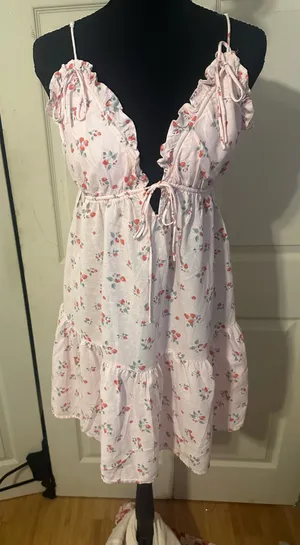 New with tags Wild Fable mini dress is a size small. This pink garment has a red strawberry print throughout. It is made of a linen-blend fabric and has adjustable spaghetti straps, a ruffled V-neckline with a tie-front detail, and a tiered skirt. thumbnail 1