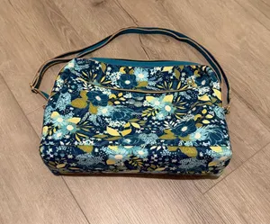 Floral Over-the-Shoulder Handbag - Like New Description Beautiful woman's shoulder bag in perfect, like-new condition! It features a vibrant blue, green, and yellow floral pattern on the exterior (as shown in image This elegant handbag is designed strictly for over-the-shoulder wear. It offers exceptional organization with an easy-access exterior zippered pocket and a spacious, spotless interior lined with a classic geometric grid pattern With absolutely zero signs of wear, this gorgeous bag looks completely brand new and is ready for its next home. Ships quickly from a smoke-free home thumbnail 1