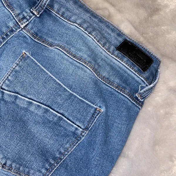 Distressed Blue Denim Jeans – Classic Streetwear Style with Branding Patch - Image 4