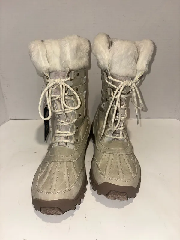 U.S. Polo Assn. Women's Yvonne Snow Boots in an "Oatmeal" or beige colorway. These mid-calf winter boots feature a duck-toe rubber shell base for slush protection, a quilted canvas shaft, traditional lace-up closure, and a plush faux-fur collar trim. A signature metallic logo plaque is attached to the side strap - Image 5