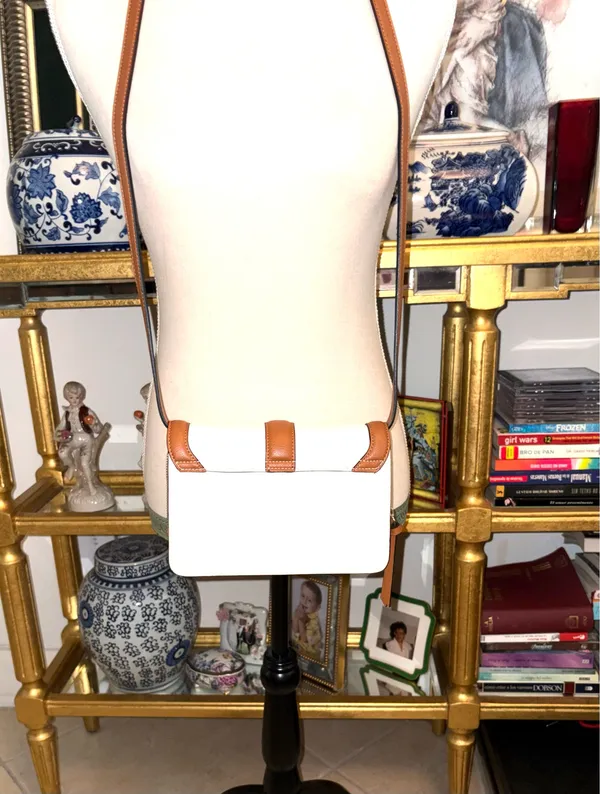 White and brown crossbody bag with adjustable strap. The design features a front flap with a brown leather detail and a clip closure. - Image 3